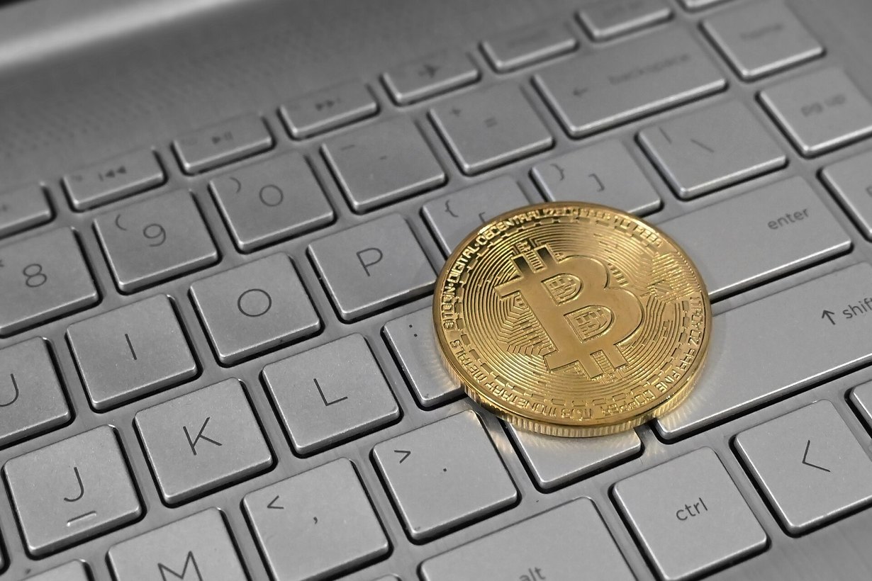 Монета биткоина на клавиатуре ноутбука